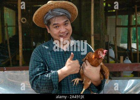 Asiatische Bauern halten Hühner. Auf einer Hühnerfarm in der eigenen Wohnung, mit einem glücklichen Geste