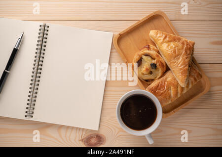 Blick von oben auf die frische Desserts und Torten auf Holz- Fächer platziert Platziert neben einem leeren Notebook und weiße Kaffeetassen. Konzept einer Bremse und relaxatio nehmen Stockfoto