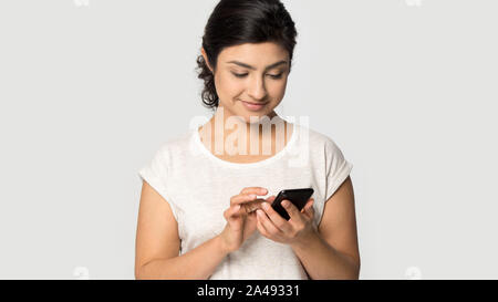 Ethnische Mädchen auf grauem Hintergrund mit Handy isoliert Stockfoto