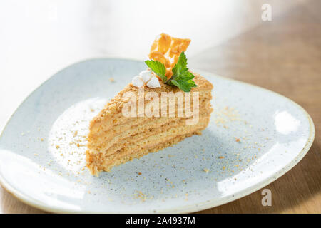 Honig Kuchen mit Baiser und Minze dekoriert. Frühstück im Café, Kaffee am Morgen. am Holztisch. Restaurant Menü Stockfoto