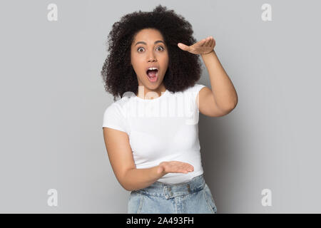 Schockiert biracial Girl Show big size Messung mit Händen Stockfoto