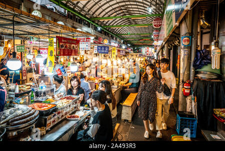 Seoul Korea, 21. September 2019: Blick auf eine Gasse der Kwangjang Markt bei Nacht mit Menschen essen Essen an Ständen Stockfoto