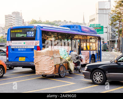 Seoul, Südkorea - 31. Mai 2017: Ein älterer Mann, der die Last auf einem Wagen, auf einem Motorrad befestigt. Die zentrale Straße in Seoul. Stockfoto