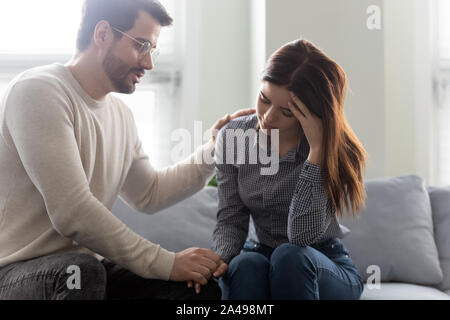 Unglücklich betonte Frau sitzt auf einem Sofa mit einfühlsamen Mann. Stockfoto