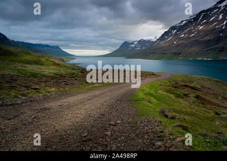 Eine isländische Schotterstraße führt zum Meer. Westfjorde Islands Stockfoto