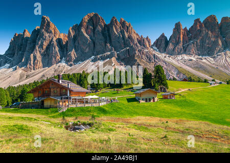 Malerische Feder Alpenlandschaft, Touristische Hütten und kleinen See mit hohen schneebedeckten Berge im Hintergrund, Geisler - Geisler Berg Gruppe, Stockfoto