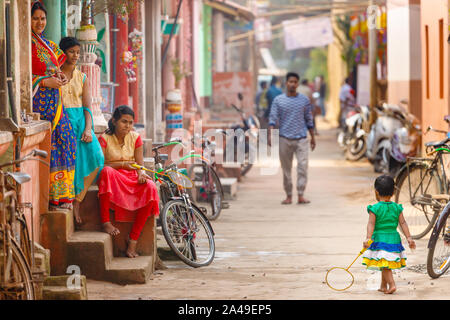 RAGHURAJPUR, Indien, 14. JANUAR 2019: Indische Damen sitzen auf Schritte beobachten Ein kleines Mädchen spielen Badminton in Raghurajpur, das Handwerk famo Stockfoto