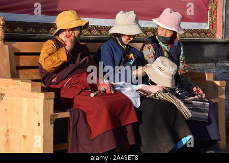 Drei alte tibetische Frauen in traditioneller Kleidung auf einer Bank in der Nähe Jokhang Tempel in Lhasa - Tibet Stockfoto