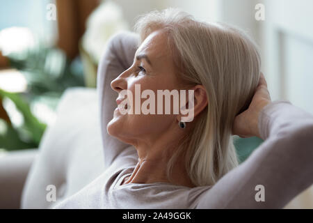 60 s Frau, die Hände hinter dem Kopf im Innenbereich Wochenende Stockfoto