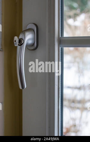 Konzept, die Sicherheit der Kinder, den Schutz des Kindes vom Fallen aus dem Fenster. Auf dem geschlossenen PVC Fenstergriff mit Schloss und Schlüssel. Close-up. Stockfoto