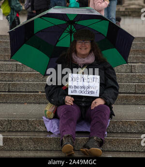 London, Großbritannien. 12. Oktober 2019. Demonstrant auf die Schritte der Trafalgar Square in der Regen während das Aussterben Rebellion zwei einwöchigen Protest in London gesehen. Credit: Joe Kuis/Alamy Nachrichten Stockfoto