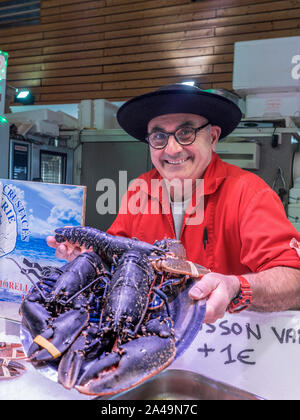 BRETON FISCHHÄNDLER & LIVE BLUE LOBSTER CLEUNES FISCH MARKTSTAND CONCARNEAU FRANKREICH BRETAGNE Concarneau täglich innen Französisch Fisch Markthalle und Charakter Fischhändler, im bretonischen Stil Outfit stolz seinen lokalen live Blue Lobster Anzeigen zum Verkauf bretagne finistere Frankreich Stockfoto