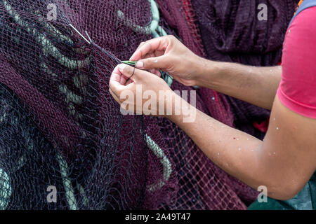 Fischer Instandsetzung Fischernetze. Fischer mit Net in den Händen ausbessern. Stockfoto