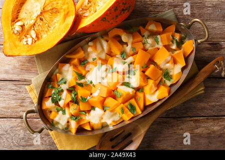 Gebacken Kürbis in Scheiben geschnitten mit Mozzarella Käse und Kräutern close-up in einer Auflaufform auf den Tisch. Horizontal oben Ansicht von oben Stockfoto