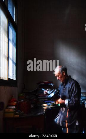 Poyang, der chinesischen Provinz Jiangxi. 12 Okt, 2019. Ding Guokun arbeitet auf einem Stück lackwaren an seinem Haus in Poyang County, der ostchinesischen Provinz Jiangxi, Okt. 12, 2019. Ding Guokun, 76, ein auf nationaler Ebene immaterielles kulturelles Erbe Erbe, hat körperlosen Lackwaren, seit er 16 war. " Halten, zu tun, eine Sache und es gut. Sie werden schließlich die Anerkennung der Menschen verdienen", sagt Ding. Credit: Hu Chenhuan/Xinhua/Alamy leben Nachrichten Stockfoto