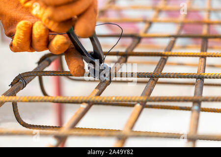 Die Bindung Verstärken von Stahl Bars für den Bau. Anziehen der Draht auf mit Hilfe einer Zange Armierungseisen. Stockfoto