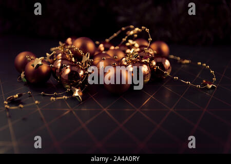 Bronze christbaumkugeln auf Hintergrund in Grün und Gold. Kugeln aufgewickelt mit goldenen Kette mit Sternen. Stockfoto