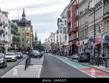 Blick auf die Straße von Geschäften, Wohnhäusern, U-Bahn Eingang & Kirchturm Karl Marx Straße, Neukölln, Berlin Stockfoto