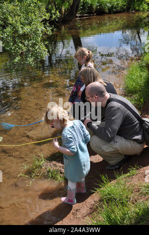 Paar und zwei Mädchen Angeln in Stream für tiddlers. Stockfoto