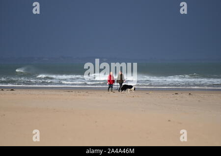Hund Spaziergänger, Bamburgh Beach, Northumberland Stockfoto