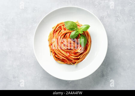 Nudeln mit Tomatensoße und Basilikum auf weißem Hintergrund. Ansicht von oben Stockfoto