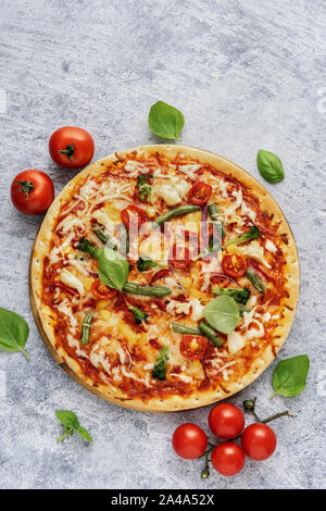 Der gesunde vegetarische Pizza mit Käse und Gemüse auf hellblauem Hintergrund. Vertikaler Dampfstoß Stockfoto