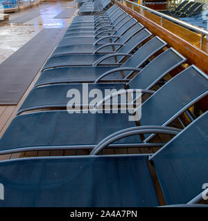 Eine Linie der Liegestühle auf einem Kreuzfahrtschiff im Morgenlicht Stockfoto