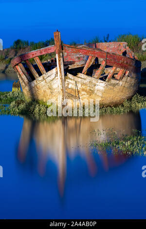 Die noirmoutier Boote Friedhof. Von den Lampen beleuchtet, das Wrack eines alten hölzernen Fischerboot auf einem Bett von Grün gestrandet in der wider Stockfoto