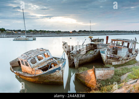 Die noirmoutier Boote Friedhof am frühen Morgen. Eine Gruppe von Wracks von alten hölzernen Fischerboote im Schlamm gestrandet, die vom Hafen ligh beleuchtet Stockfoto