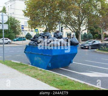 Eine vollständige Müllcontainer mit Müllsäcken steht auf der Straße Straße Stockfoto