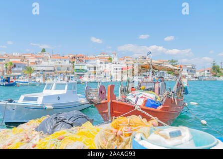 Ermioni Griechenland - 20 Juli 2019; Waterfront mit orange boat im Vordergrund und seinen malerischen Angeln Boote entlang Pier und dem Gebäude hinter. Stockfoto