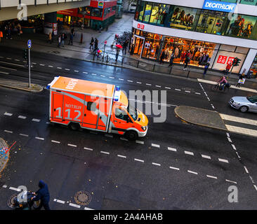 Berlin, Deutschland - 5. Oktober 2019: Krankenwagen der Feuerwehr in einer belebten Einkaufsstraße in Berlin-Steglitz im regnerischen Wetter während einer Mission dri Stockfoto