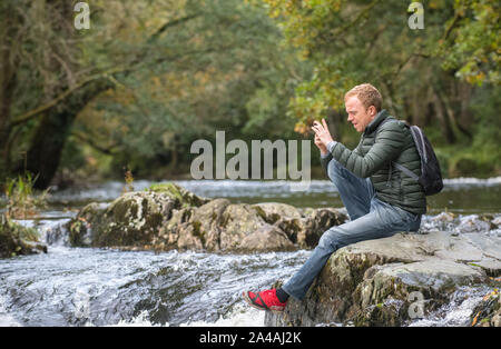 Mann auf dem felsigen Ufern des Pont-y-Paar fällt auf die Afon Llugwy, Betws-y-Coed, Wales, Großbritannien Stockfoto