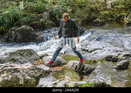 Mann auf dem felsigen Ufern des Pont-y-Paar fällt auf die Afon Llugwy, Betws-y-Coed, Wales, Großbritannien Stockfoto