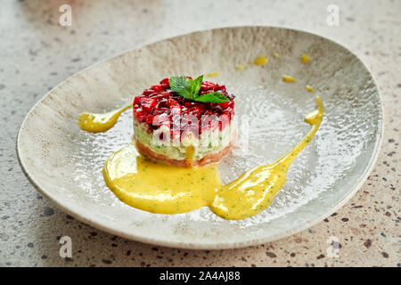 Lecker Lachstatar mit gelber Soße auf dem Teller im modernen Restaurant serviert. Stockfoto