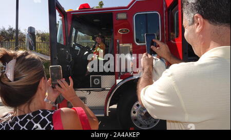 Eltern machen Sie Fotos von Ihrem Kind, wie Sie erhalten das Löschfahrzeug im Fire Station open house zu erkunden Stockfoto