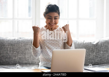 Indische Frau feiern Gewinnen aufgeregt, auf der Suche nach Laptop Bildschirm Stockfoto