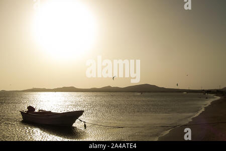 Golden Beach Landschaft am goldenen Licht Sonnenuntergang mit Boot am Ufer, ruhige See und Bergen im Hintergrund, Stockfoto