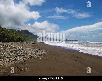 Landschaft der Sandstrand in der Kolumbianischen Naturpark, über Karibische Meer mit Wellen und Dschungel Vegetation. Ein sonniger Tag mit Wolken. Tayrona National Par Stockfoto