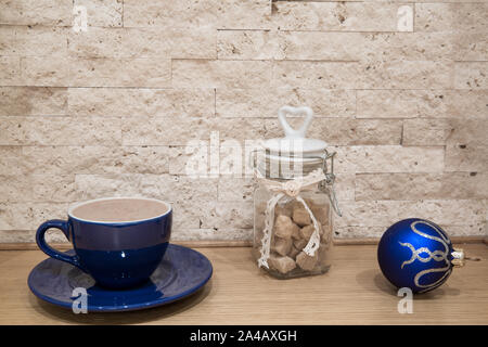 Blaue Tasse mit heißer Schokolade (Kakao) und Silber Weihnachten Dekoration, weiße und blaue Weihnachtskugeln, Zuckerrohr brauner Zucker, Weihnachten Hintergrund. Stockfoto