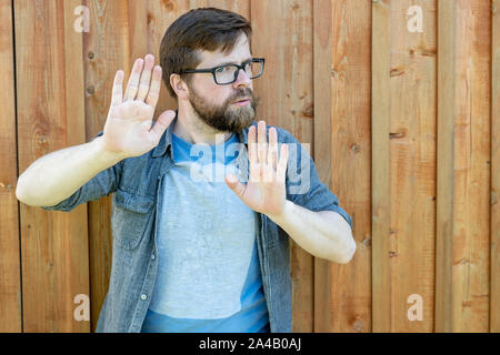 Ein ruhiger, selbstbewusster bärtiger Mann pus seine Handflächen als Verteidigung oder Beruhigenden jemand unten und der Blick in die Kamera. Auf einem bemalten alten ba Isoliert Stockfoto