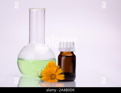 Dunkle kosmetische Flasche aromatisches Öl für pflanzliche Arzneimittel mit Calendula flower auf weißen Hintergrund isoliert. Ringelblumen Extrakt. Stockfoto