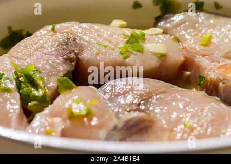 Marinierte Schwertfisch in einer Schüssel mit Zitronensaft, Öl, Knoblauch, Petersilie Stockfoto