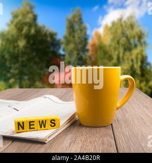 Morgen aktuelles Konzept - Kaffeetasse, Zeitung auf hölzernen Tisch über Herbst bunte hintergrund Stockfoto