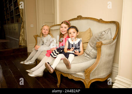 Die Kinder saßen auf einem Stuhl in der party Kleider Stockfoto