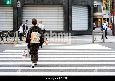 Tokio, Japan - OKTOBER 6, 2018. Japanische Frau ist der Kreuzung Straße tragen traditionelle japanische Kleid. Dame im Kimono auf der Straße in Tokio. Stockfoto