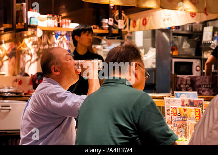 Tokio, Japan - OKTOBER 6, 2018. Männer haben das Abendessen und Bier trinken im japanischen Restaurant. Alte Freunde sind in Essen. Stockfoto