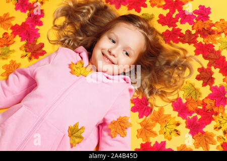 Blick von oben auf ein glückliches fröhliche kleine Mädchen liegt auf der Blätter im Herbst. Stockfoto