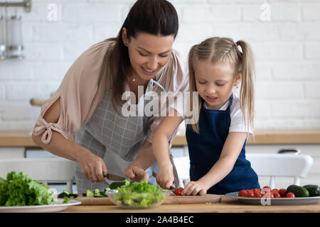 Fürsorgliche Mutter Lehre kleine Tochter Salat zu kochen Stockfoto