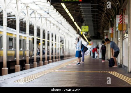 Verwischt die Menschen sind auf der Plattform auf einem Bahnhof in Tokio, Japan. Stockfoto